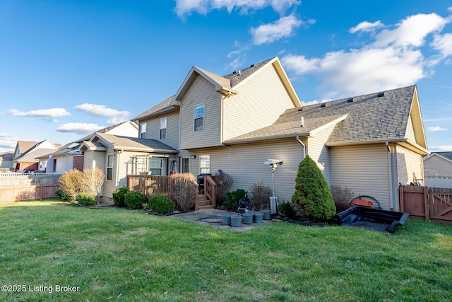 rear view of house featuring a shingled roof, a patio, a yard, fence, and a wooden deck