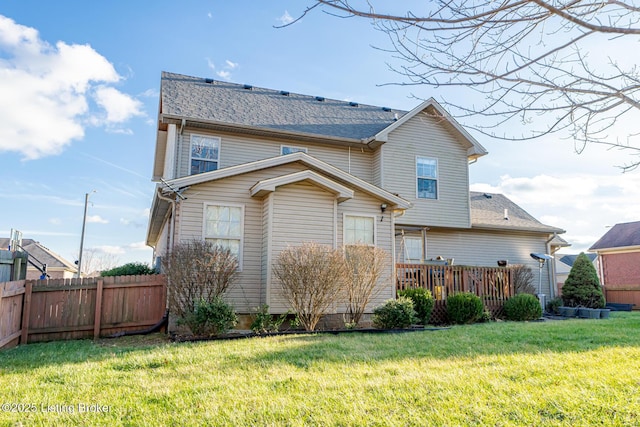 back of house featuring a deck, a shingled roof, a lawn, and fence