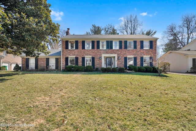 colonial home featuring a front lawn, a chimney, and brick siding