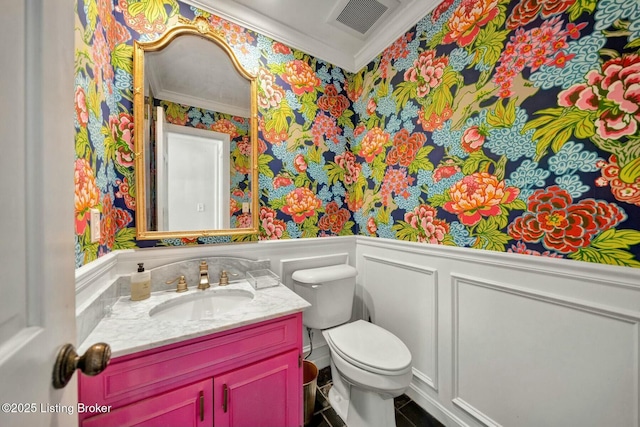 half bath with a wainscoted wall, ornamental molding, toilet, and vanity