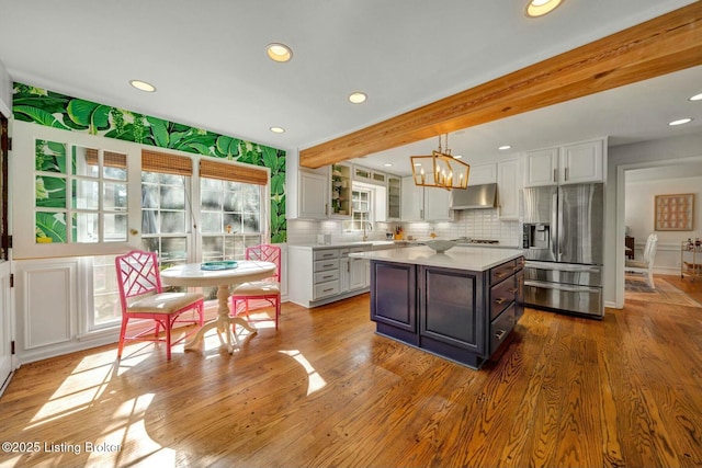 kitchen featuring light countertops, extractor fan, stainless steel fridge, and white cabinetry