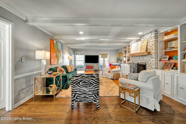 living area with beam ceiling, crown molding, a stone fireplace, and wood finished floors