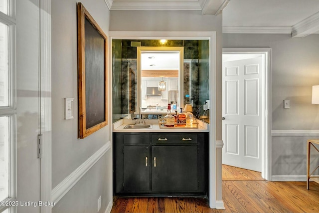 bar with tasteful backsplash, baseboards, ornamental molding, wood finished floors, and a sink