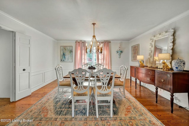 dining space with crown molding, wood finished floors, and a notable chandelier