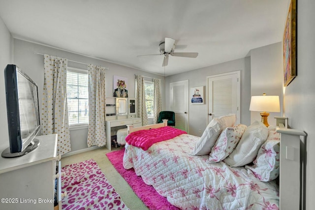 carpeted bedroom with a ceiling fan and multiple closets