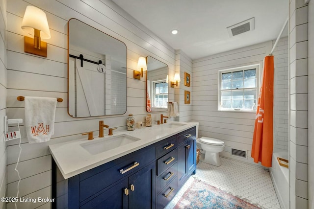 bathroom with toilet, a shower with shower curtain, a sink, and visible vents