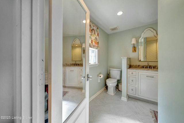 bathroom featuring two vanities, visible vents, a sink, and toilet