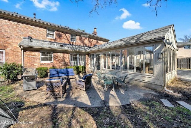 rear view of house with a patio area, outdoor lounge area, a sunroom, and brick siding