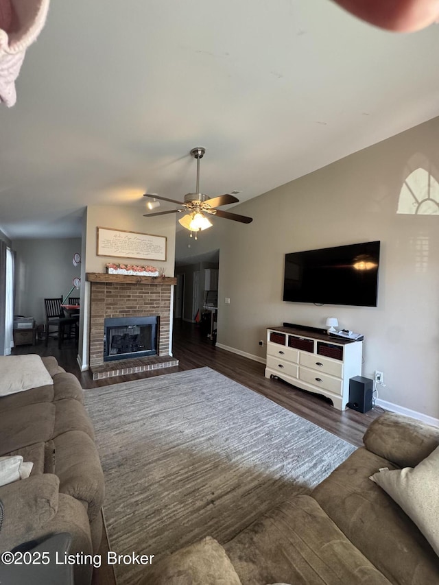 living area with lofted ceiling, a brick fireplace, dark wood finished floors, and baseboards