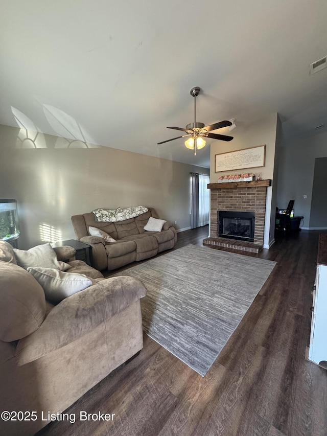 living room featuring vaulted ceiling, dark wood-type flooring, a brick fireplace, and visible vents