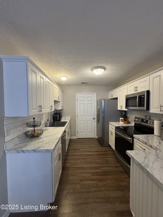 kitchen with dark wood-style floors, tasteful backsplash, appliances with stainless steel finishes, and white cabinets