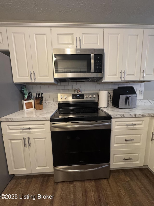 kitchen with appliances with stainless steel finishes, dark wood finished floors, and white cabinets