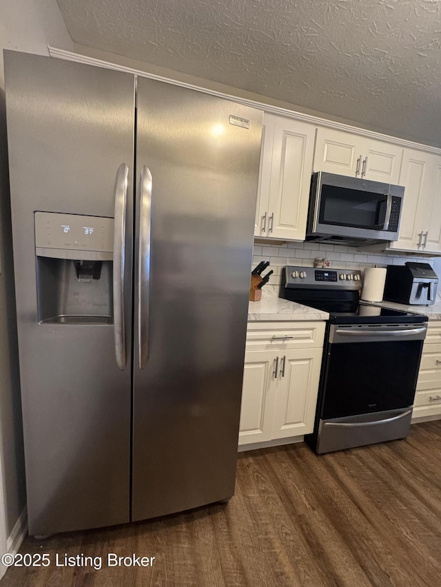 kitchen featuring tasteful backsplash, appliances with stainless steel finishes, dark wood-type flooring, white cabinets, and light stone countertops