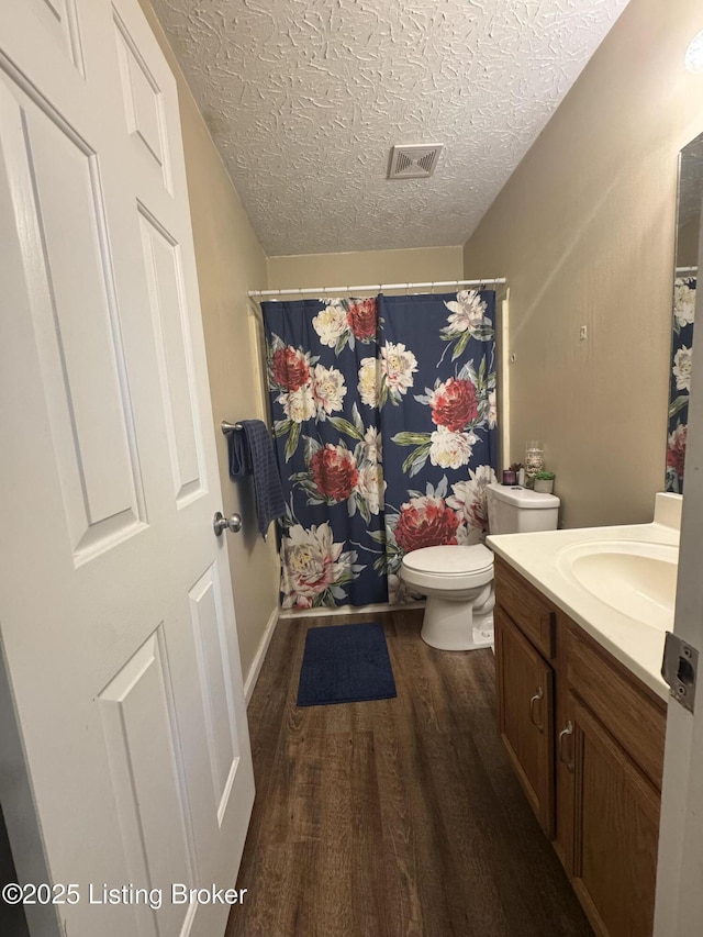 full bath with visible vents, toilet, wood finished floors, a textured ceiling, and vanity