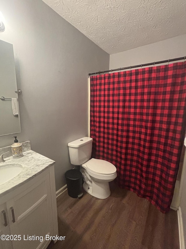 bathroom featuring a textured ceiling, curtained shower, toilet, wood finished floors, and vanity