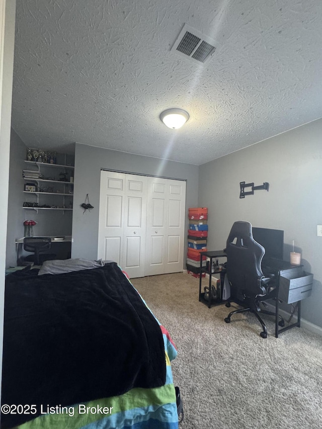 carpeted bedroom with a textured ceiling, visible vents, and a closet