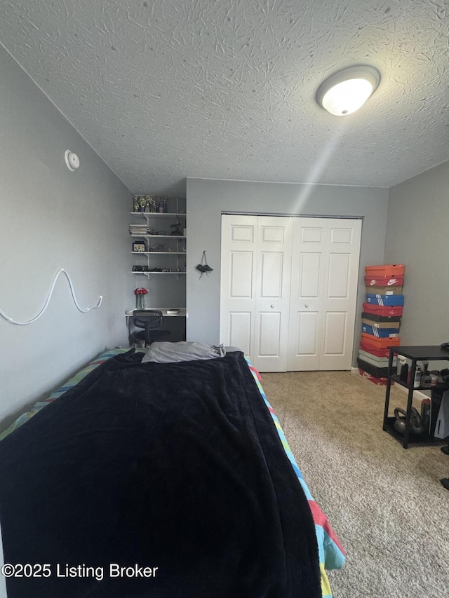 carpeted bedroom featuring a textured ceiling and a closet