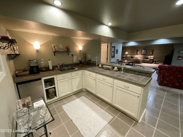 kitchen with tile counters, a sink, a peninsula, and tile patterned floors