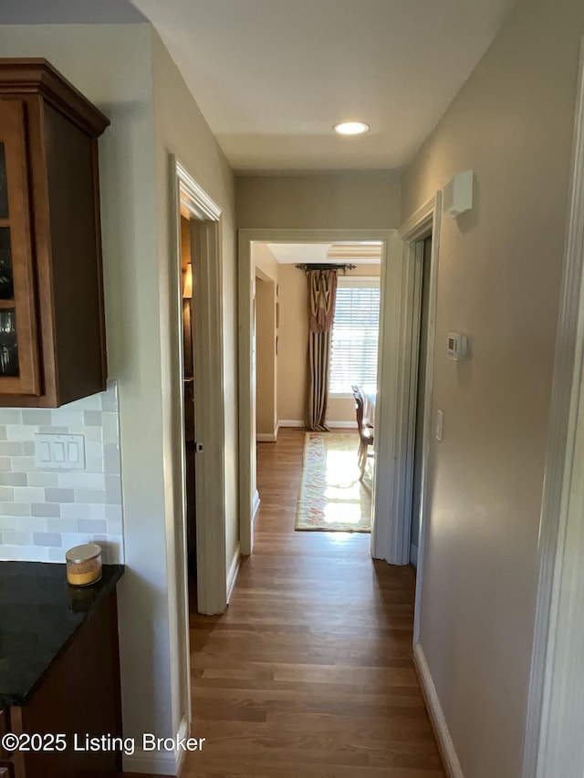 corridor featuring baseboards, wood finished floors, and recessed lighting