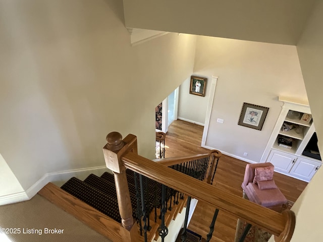 stairs with a high ceiling, wood finished floors, and baseboards