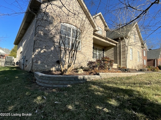 view of side of home featuring brick siding and a yard