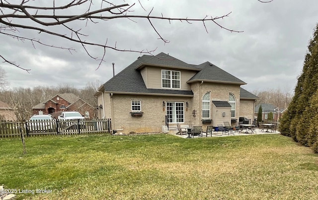 rear view of house with a patio, a yard, fence, and brick siding