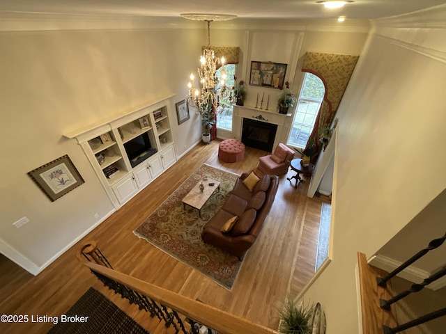 living area with a chandelier, a fireplace, baseboards, and wood finished floors