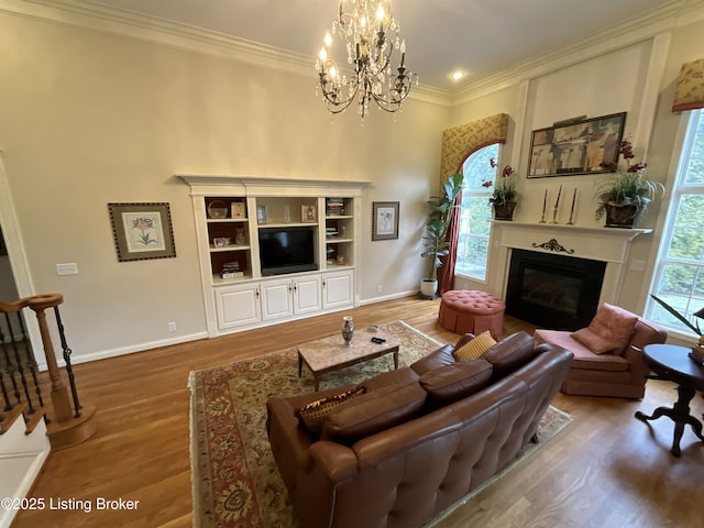 living room with a wealth of natural light, a glass covered fireplace, crown molding, and wood finished floors