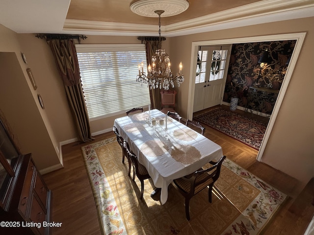 dining room with a raised ceiling, baseboards, and wood finished floors