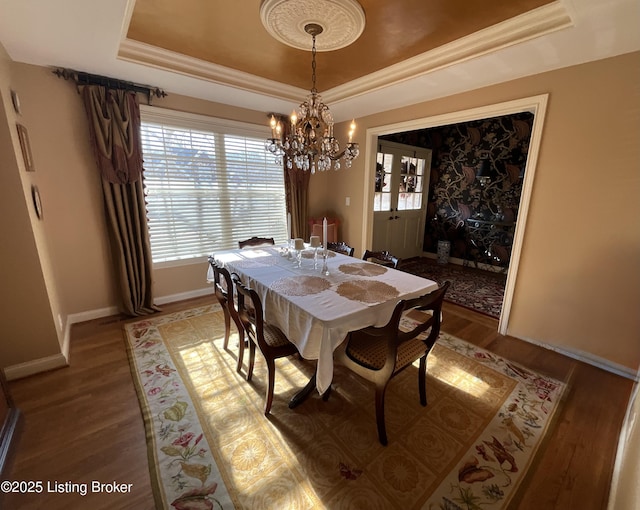 dining area featuring light wood finished floors, ornamental molding, and a raised ceiling