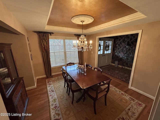 dining room with baseboards, a tray ceiling, a chandelier, and wood finished floors