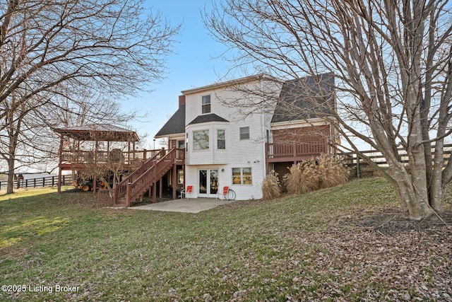 back of house featuring a lawn, a chimney, stairs, and a patio area