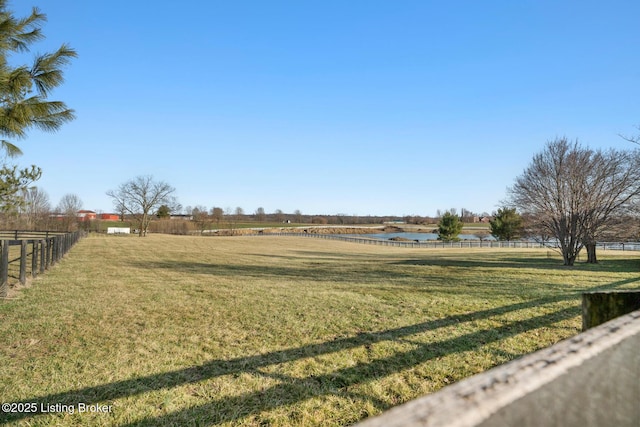 view of yard featuring a rural view, a water view, and fence