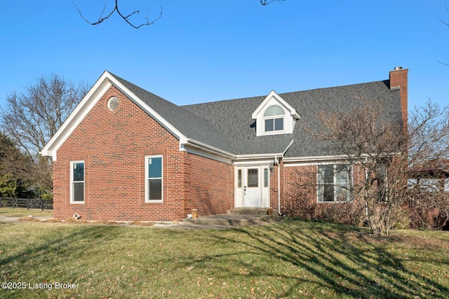 cape cod home with fence, a shingled roof, a chimney, a front lawn, and brick siding