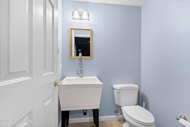 half bathroom featuring toilet, vanity, and baseboards