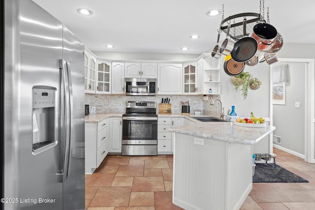 kitchen with a sink, tasteful backsplash, appliances with stainless steel finishes, and a peninsula