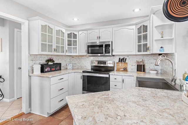 kitchen with backsplash, appliances with stainless steel finishes, white cabinetry, and a sink