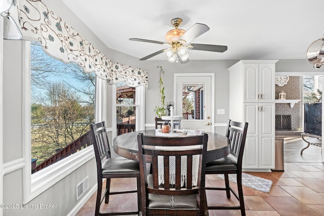 dining space featuring light tile patterned floors, visible vents, a ceiling fan, and a fireplace