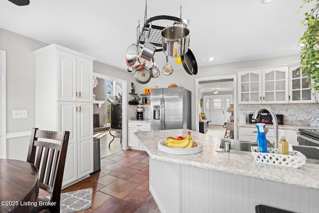 kitchen featuring white cabinets, glass insert cabinets, stainless steel fridge, and a wealth of natural light