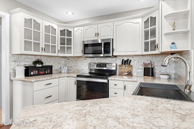 kitchen featuring a sink, decorative backsplash, light countertops, appliances with stainless steel finishes, and white cabinetry