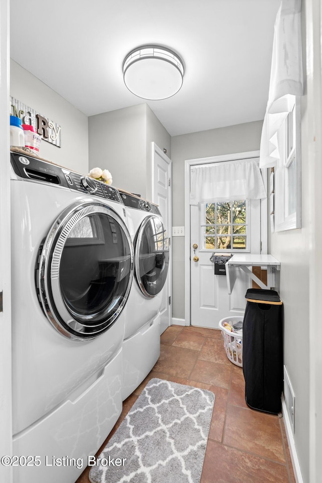 laundry room with baseboards, visible vents, laundry area, stone tile flooring, and washer and clothes dryer