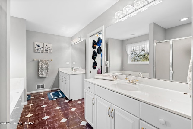 bathroom featuring a sink, a garden tub, two vanities, and tile patterned floors