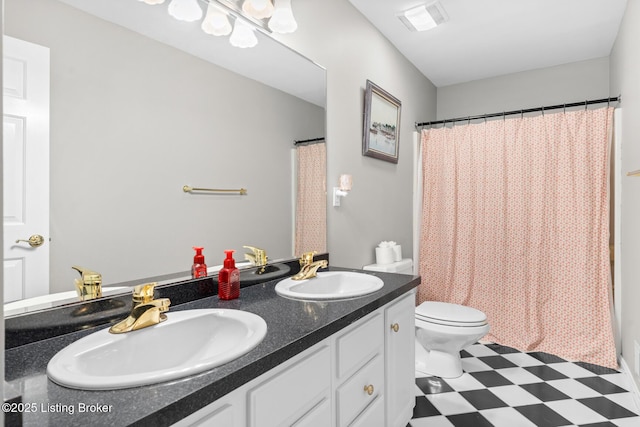 bathroom with tile patterned floors, double vanity, toilet, and a sink