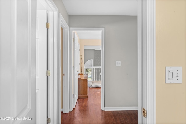 corridor featuring baseboards and dark wood-type flooring