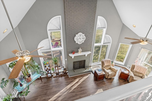 living room featuring a ceiling fan, a brick fireplace, wood finished floors, and high vaulted ceiling