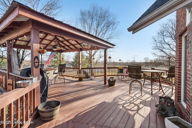 deck with a gazebo, outdoor dining space, and a ceiling fan