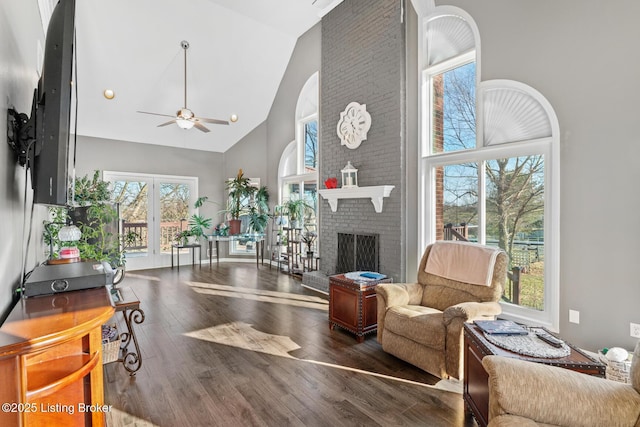 living area with ceiling fan, wood finished floors, a fireplace, and high vaulted ceiling