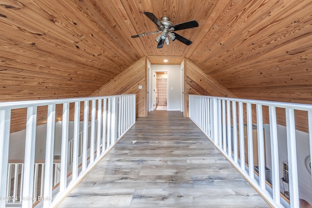 hallway with wooden ceiling, wood walls, vaulted ceiling, and wood finished floors