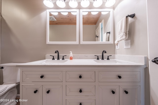 full bathroom with visible vents, a sink, toilet, and double vanity