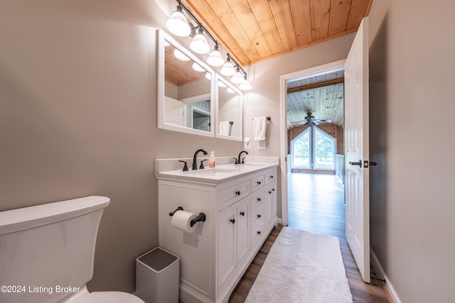 bathroom with double vanity, baseboards, toilet, wood ceiling, and a sink